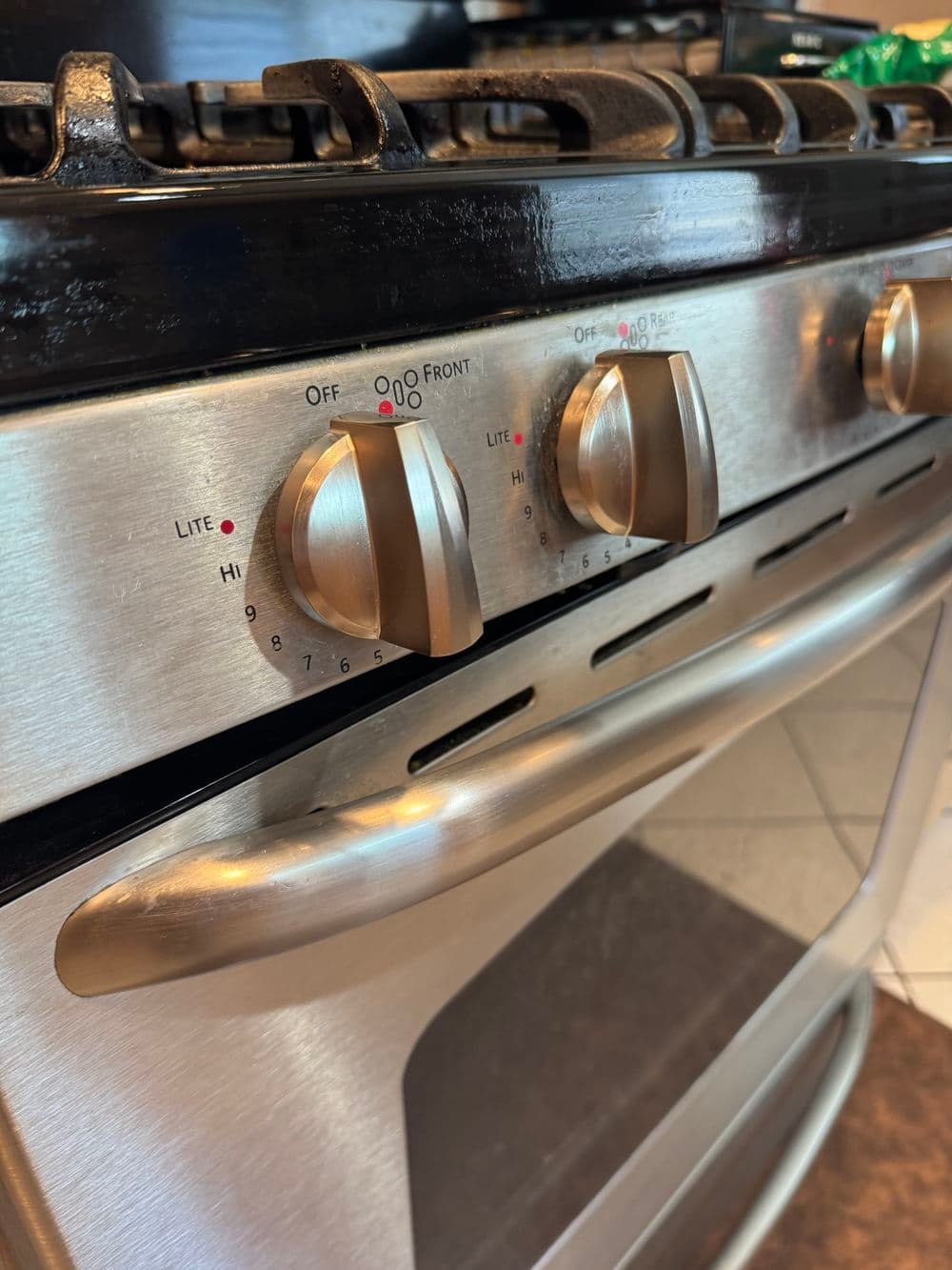 Stainless steel gas stove with control knobs, showcasing temperature settings and design details.